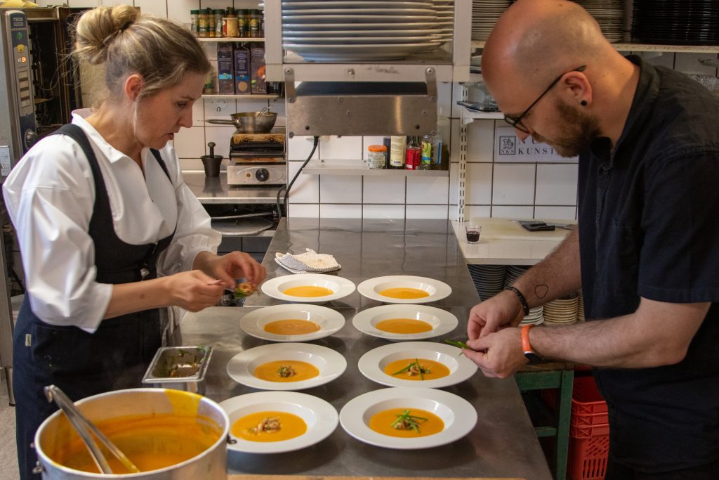 Solveig Barstad og en kollega legger opp suppe på kjøkkenet på Nutheim Gjestgiveri.