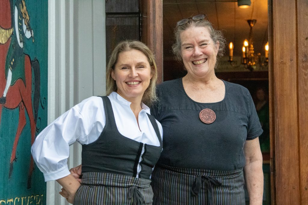 Solveig Barstad og Ellen Grøstad Barstad smiler ved inngangen til Nutheim Gjestgiveri.