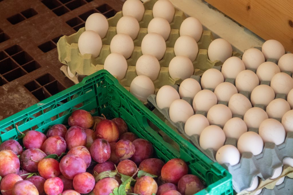 Brett med egg og en grønn kasse med røde og lilla plommer fra Størsrud gård.